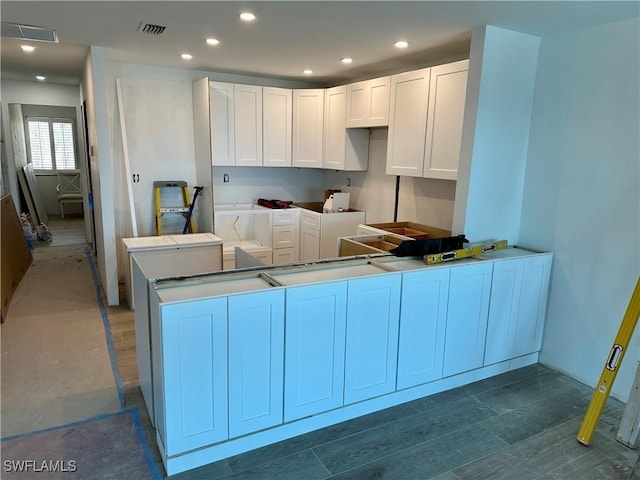 kitchen featuring visible vents, recessed lighting, a peninsula, wood finished floors, and white cabinetry