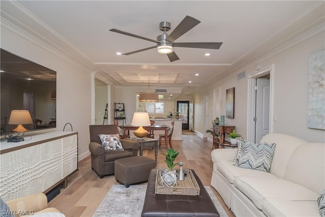 living room featuring light wood-type flooring, a ceiling fan, visible vents, and ornamental molding