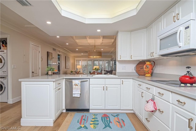 kitchen with stacked washer / dryer, dishwasher, decorative light fixtures, kitchen peninsula, and white cabinets