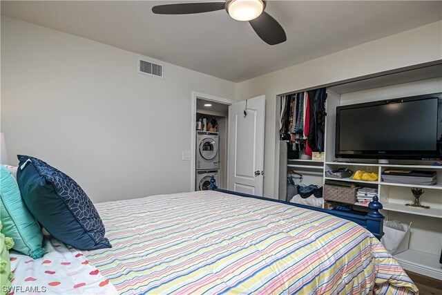 bedroom with ceiling fan, stacked washer and dryer, and a closet