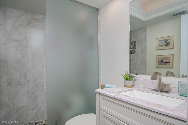 bathroom featuring vanity, a tile shower, and toilet