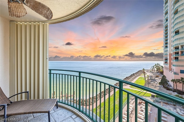 balcony at dusk featuring a water view