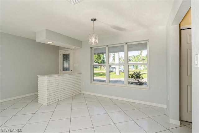 spare room featuring light tile floors and an inviting chandelier