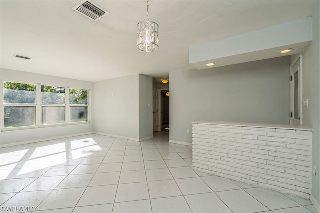 tiled empty room with a notable chandelier