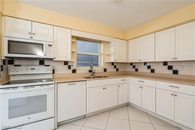 kitchen with backsplash, white appliances, white cabinetry, and sink