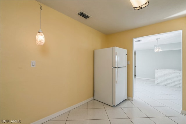 kitchen with an inviting chandelier, hanging light fixtures, light tile flooring, and white fridge