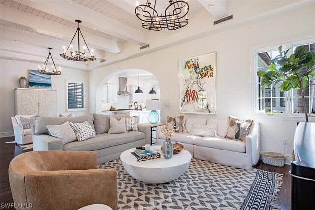 living room featuring an inviting chandelier, beam ceiling, hardwood / wood-style flooring, and sink