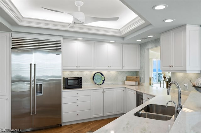 kitchen featuring white cabinetry, built in fridge, wood-type flooring, and light stone counters