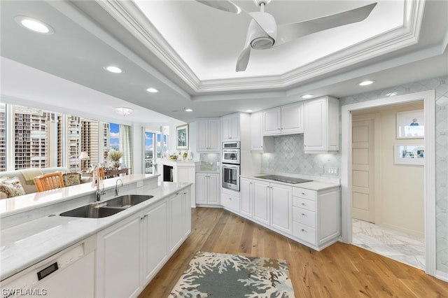 kitchen with ceiling fan, sink, light hardwood / wood-style flooring, white cabinets, and a raised ceiling