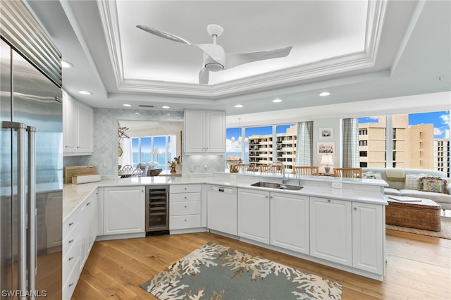 kitchen with kitchen peninsula, ceiling fan, built in fridge, beverage cooler, and tasteful backsplash