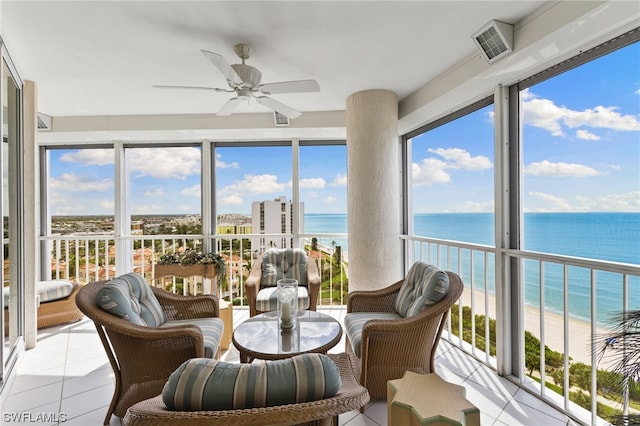 sunroom featuring a view of the beach, ceiling fan, and a water view