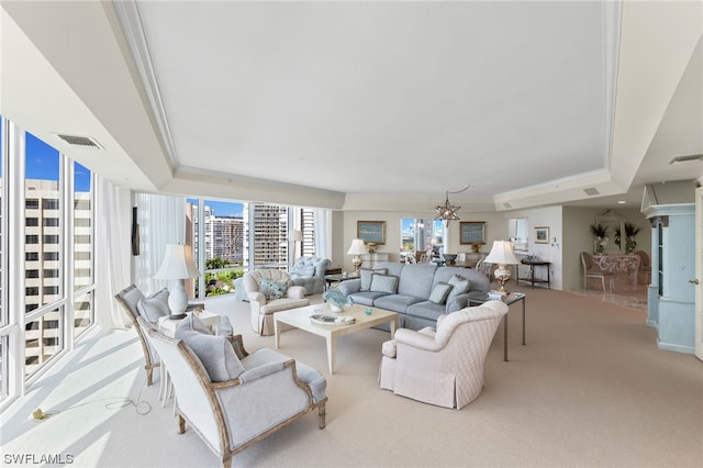 carpeted living room featuring an inviting chandelier, crown molding, and a raised ceiling