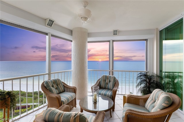 sunroom / solarium with ceiling fan and a water view