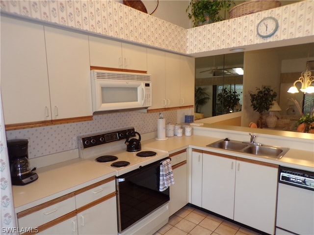 kitchen with sink, white appliances, light tile floors, and white cabinetry