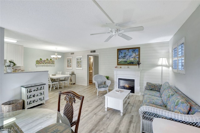 living room featuring a textured ceiling, light hardwood / wood-style floors, a fireplace, and wooden walls