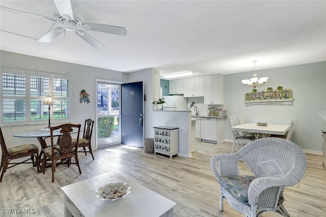 living room featuring a textured ceiling, ceiling fan with notable chandelier, and light hardwood / wood-style flooring