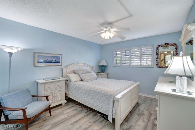 bedroom with light wood-type flooring, ceiling fan, and a textured ceiling