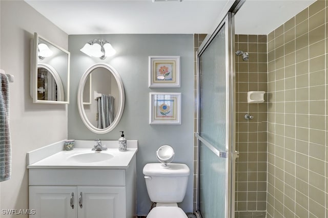 bathroom featuring toilet, a shower with door, and vanity