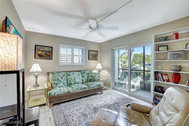 living area with wood-type flooring, a textured ceiling, and ceiling fan