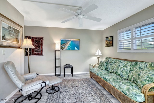 living room with ceiling fan, wood-type flooring, and a textured ceiling