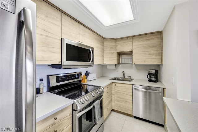 kitchen with sink, light tile flooring, light brown cabinetry, and appliances with stainless steel finishes