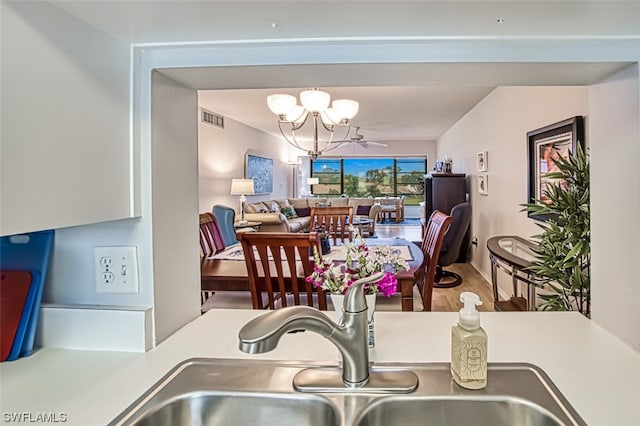 dining room with ceiling fan with notable chandelier, sink, and hardwood / wood-style flooring