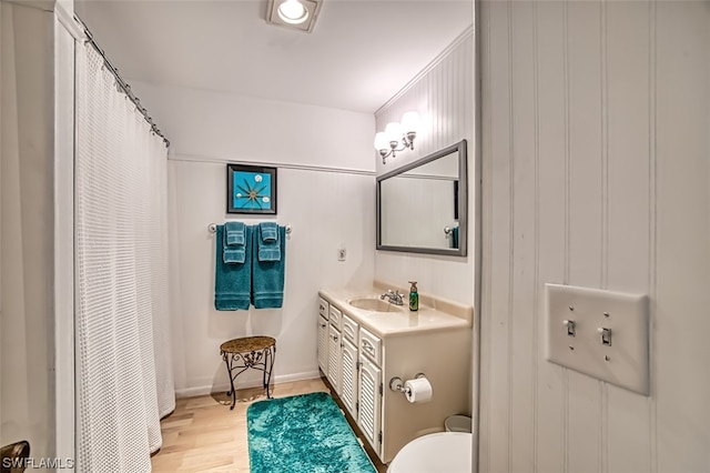 bathroom featuring hardwood / wood-style floors, vanity with extensive cabinet space, and toilet