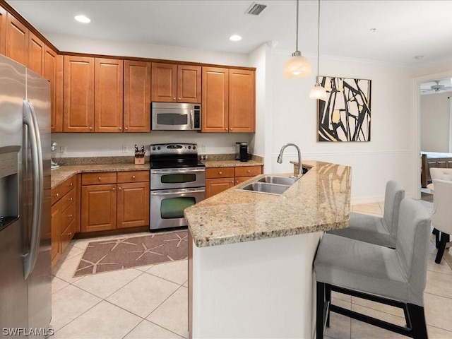 kitchen featuring light tile patterned flooring, sink, hanging light fixtures, appliances with stainless steel finishes, and light stone countertops