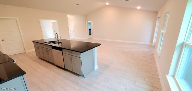 kitchen featuring lofted ceiling, dishwasher, a kitchen island with sink, light hardwood / wood-style floors, and sink