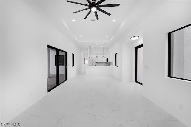 hallway with light tile floors and a raised ceiling