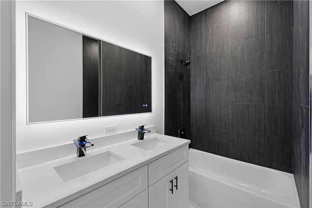 bathroom featuring tiled shower / bath, vanity with extensive cabinet space, and dual sinks