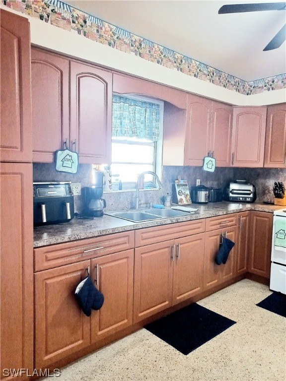 kitchen with tasteful backsplash, range, ceiling fan, and sink