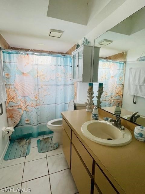 bathroom featuring toilet, vanity with extensive cabinet space, and tile flooring