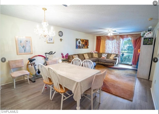 dining space featuring a textured ceiling, wood-type flooring, and ceiling fan with notable chandelier