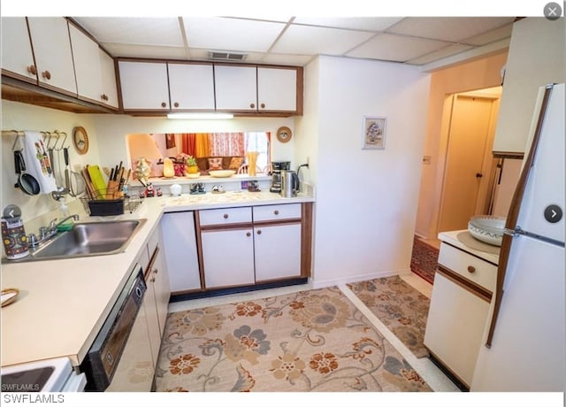 kitchen with sink, white fridge, light tile floors, white cabinets, and a paneled ceiling