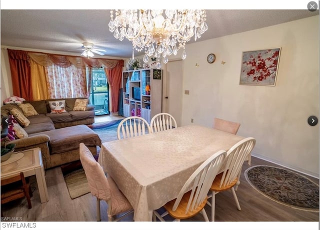 dining area featuring wood-type flooring and ceiling fan with notable chandelier