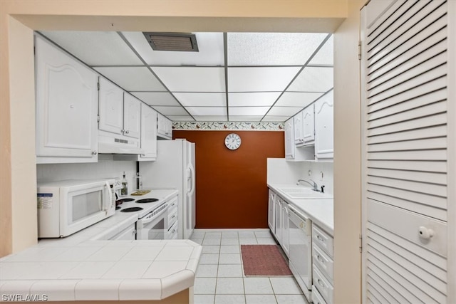 kitchen featuring sink, white appliances, white cabinets, and tile counters