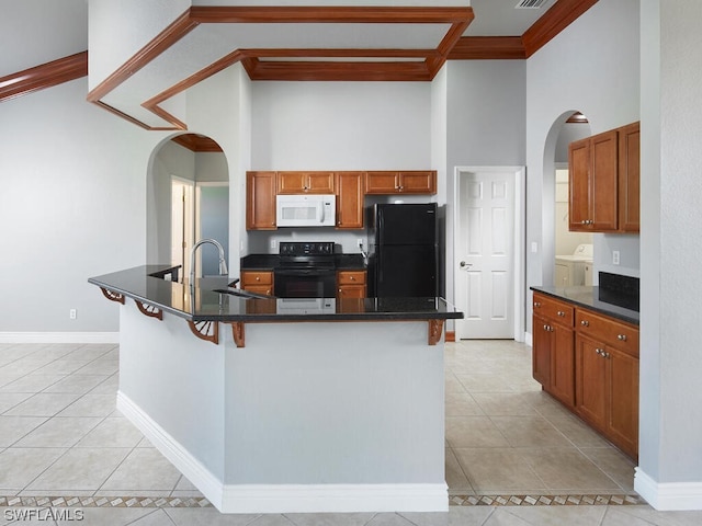 kitchen with black refrigerator, range, separate washer and dryer, and light tile flooring