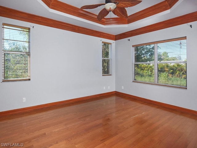 spare room with a raised ceiling, crown molding, ceiling fan, and hardwood / wood-style flooring