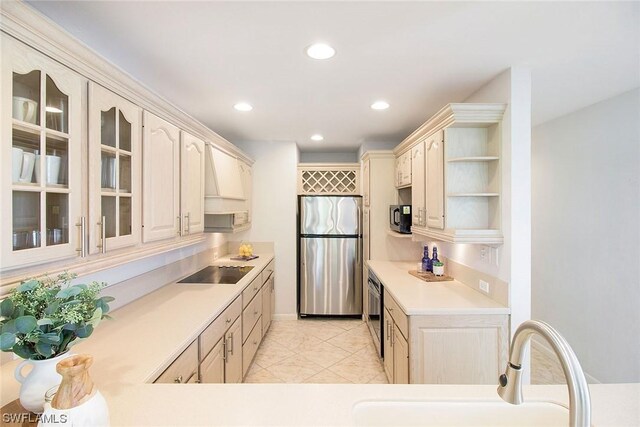 kitchen featuring light countertops, glass insert cabinets, a sink, stainless steel fridge, and black electric cooktop