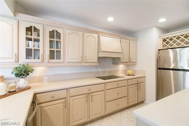 kitchen with light countertops, custom range hood, glass insert cabinets, freestanding refrigerator, and black electric cooktop