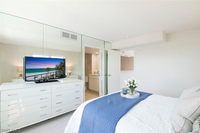 bedroom with light carpet, ensuite bath, and visible vents