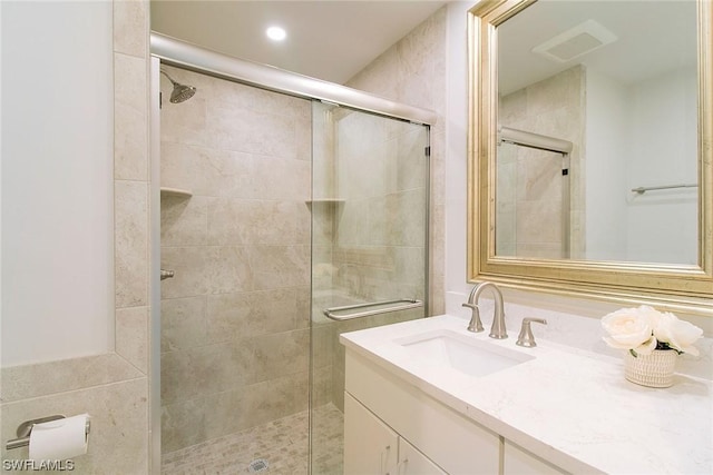 bathroom with visible vents, a shower stall, and vanity