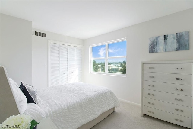 bedroom featuring baseboards, a closet, visible vents, and light colored carpet