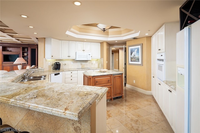 kitchen with kitchen peninsula, white cabinets, sink, light stone counters, and white appliances