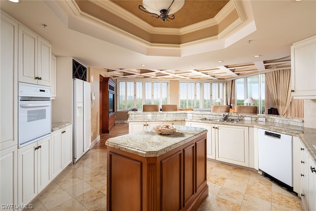 kitchen featuring white appliances, ornamental molding, kitchen peninsula, and white cabinets