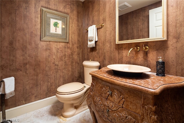 bathroom featuring vanity, toilet, and wood walls