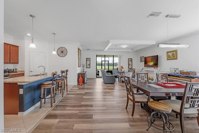 dining space featuring crown molding, light hardwood / wood-style floors, and sink