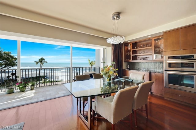 dining area featuring dark hardwood / wood-style flooring, a water view, and a notable chandelier