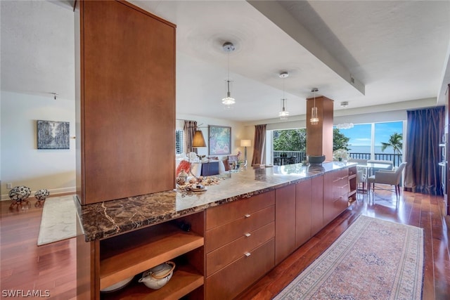 kitchen with hanging light fixtures, dark wood-type flooring, and dark stone countertops